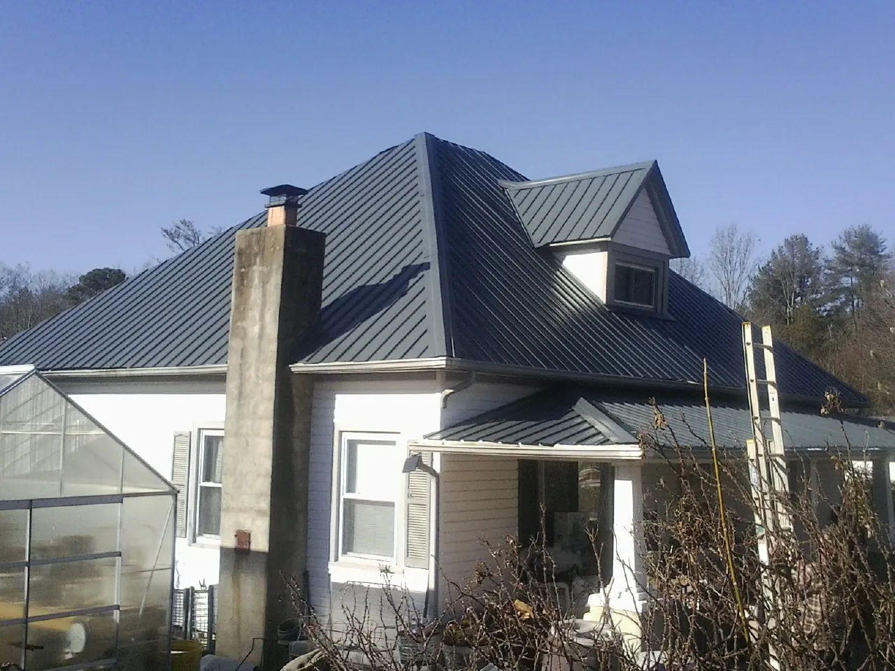 Dark blue standing seam metal roof on a white farmhouse with dormer — Slate & Tile Roof Repair by Roofing Brothers in Bel Air