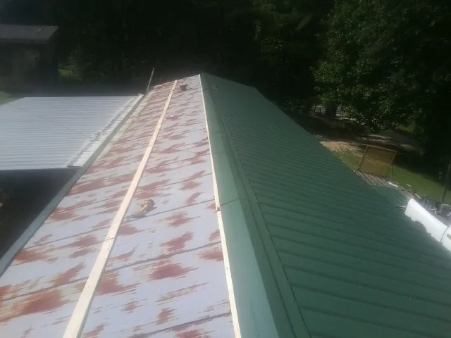 Old rusted panels beside newly installed green metal roofing — Wind Damage Roof Repair by Roofing Brothers in Bel Air