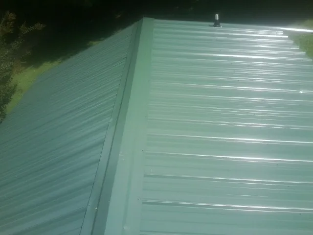 New green metal panels meeting at the ridge of a roof — Flat Roof Repair work by our crew in Bel Air