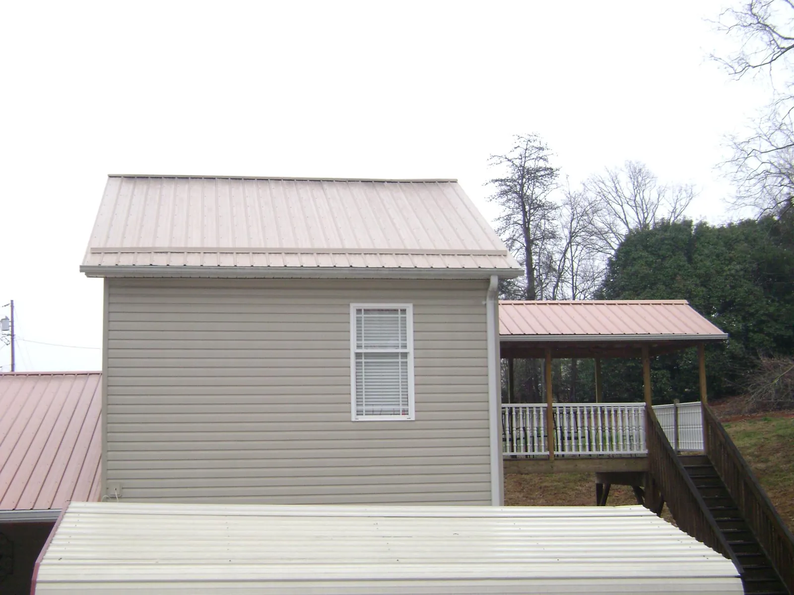 Tan metal roofs on a two story addition and attached porch, from a Roof Replacement job in Bel Air