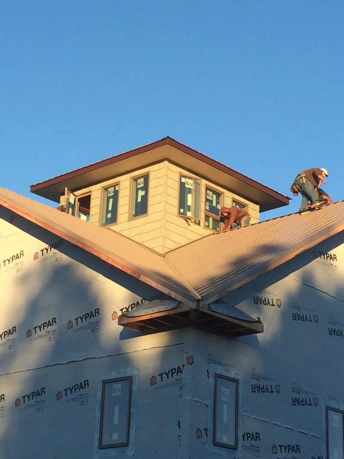 Roofers working around a rooftop cupola on a new metal roof at sunset — Roof Waterproofing in Bel Air by Roofing Brothers